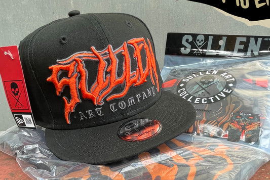 Sullen new era hat in black and orange laying on a rusty trailer