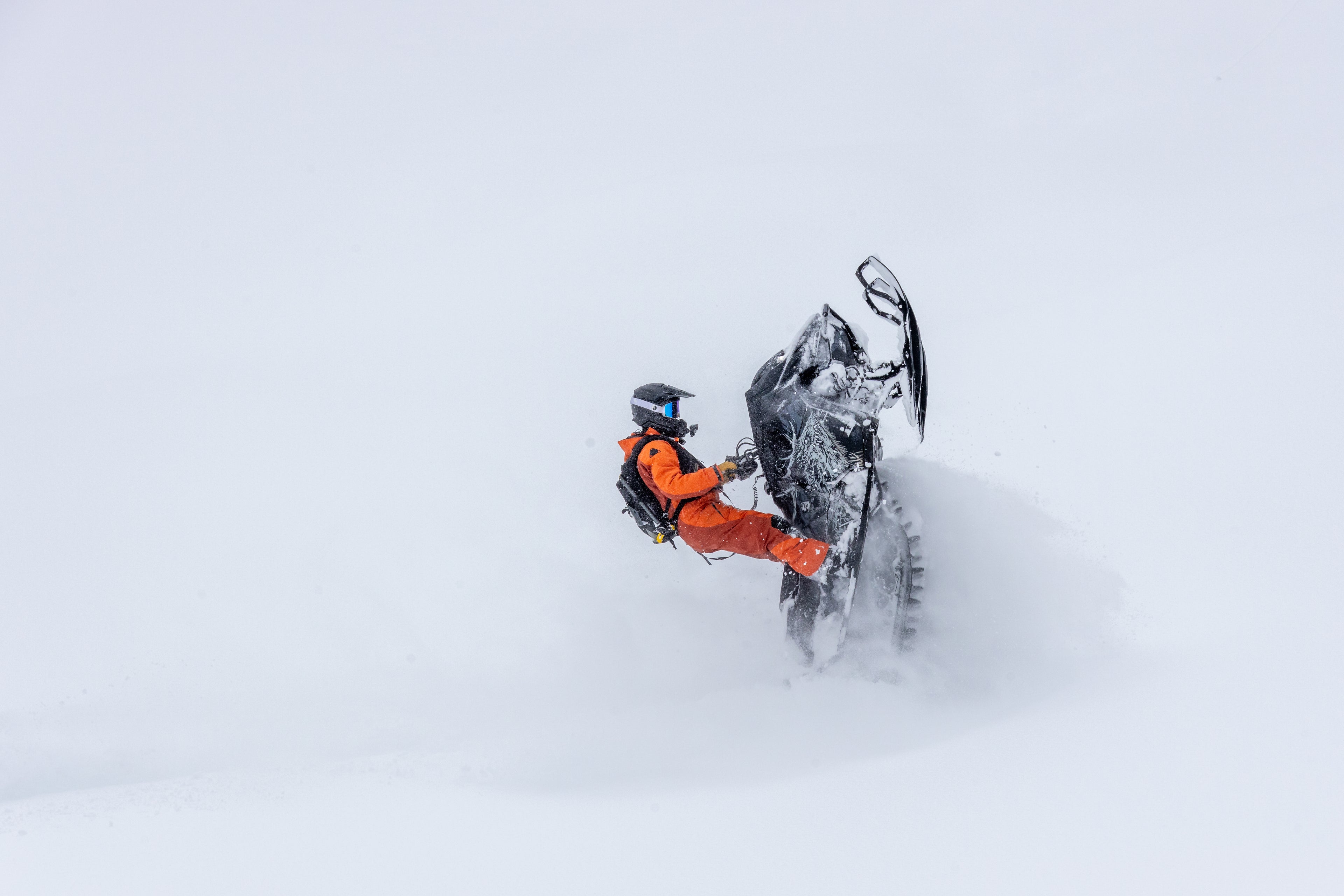 Person on a snowmobile wheelie in a snowy landscape