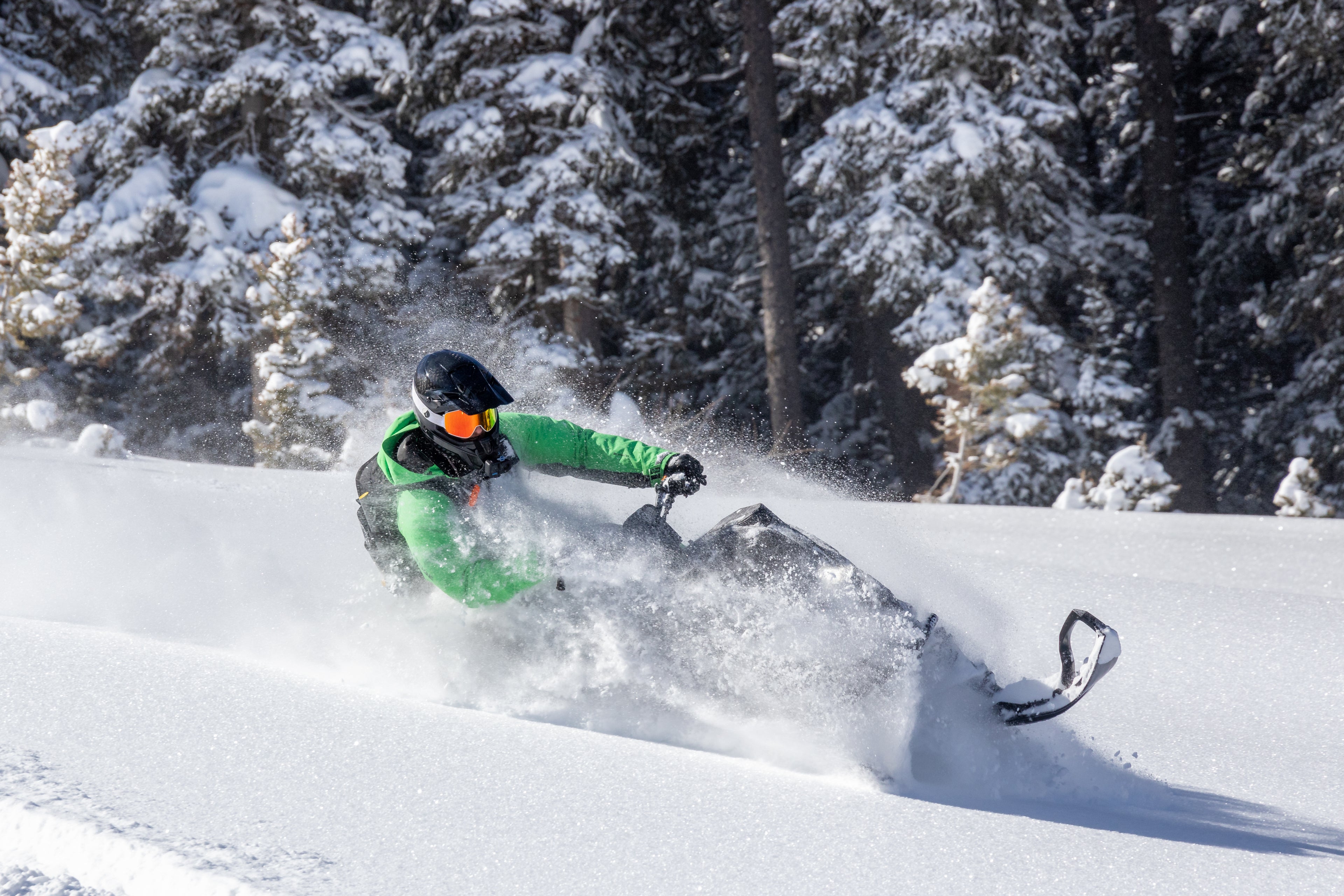 Person snowmobiling through a snowy landscape with trees in the background