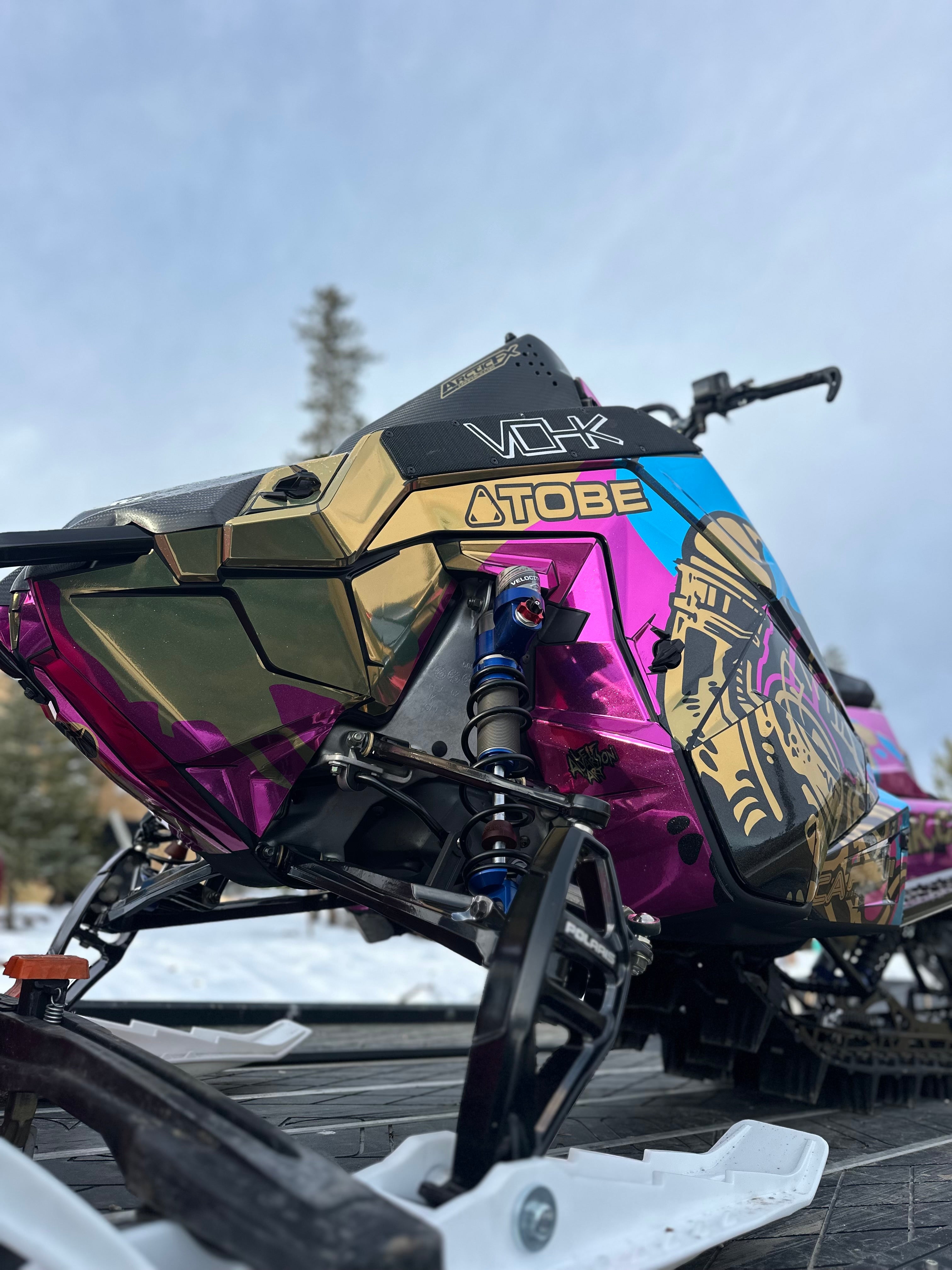 Colorful snowmobile with visible branding on a snowy landscape in chrome